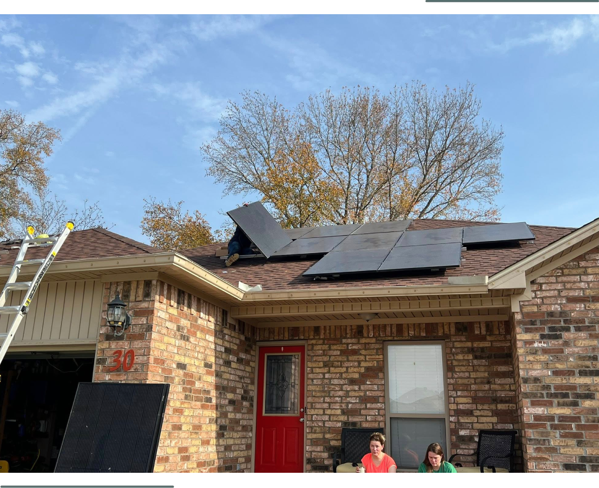 House with solar panels on the roof and people sitting outside.