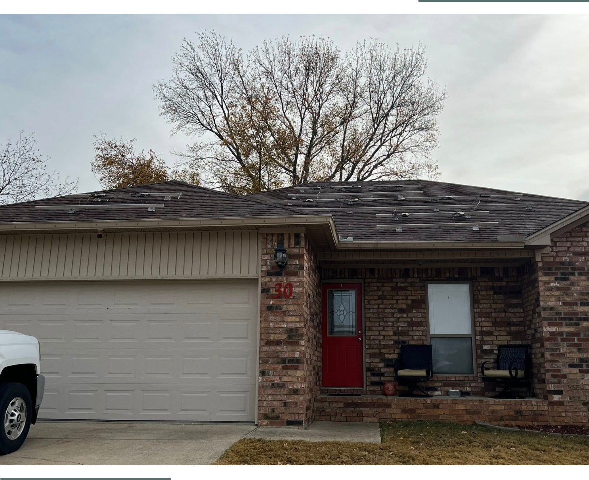 Suburban house with brick facade, white garage door, and a red front door under a cloudy sky.